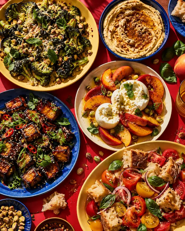 A table of finished dishes seen from above: salads, dips and little plates in vivid colour